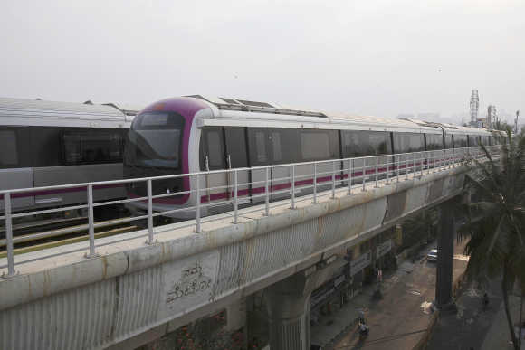 A Namma Metro train travels along an elevated track in the Indira Nagar area of Bangalore.