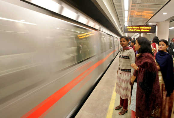 Passengers wait to board Metro train in New Delhi.