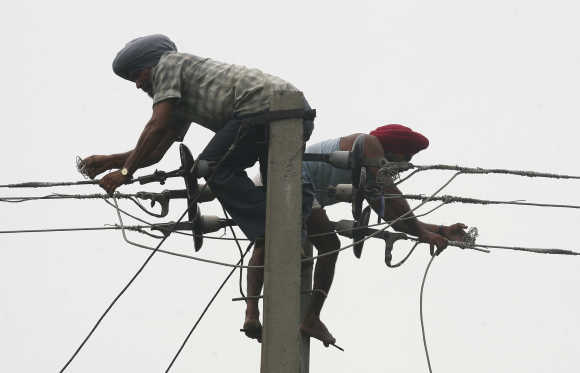 Workers repair high voltage power lines at Fatehpur Sylwa in Punjab.