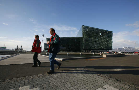 People walk past the recently opened Harpa Concert Hall in downtown Reykjavik.