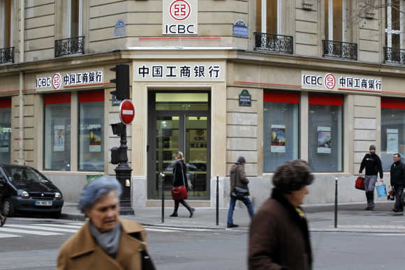 People walk past the entrance of the Industrial and Commercial Bank of China in Paris.