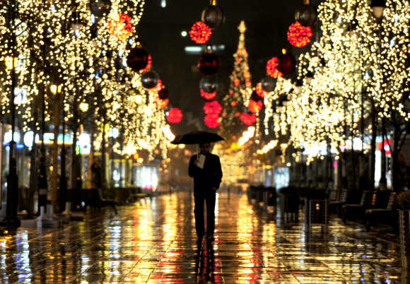 A man walks near trees illuminated with Christmas lights in the Macedonian capital of Skopje.