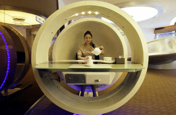 A waitress poses inside an egg-shaped dining booth at an A380 theme restaurant in Chongqing.