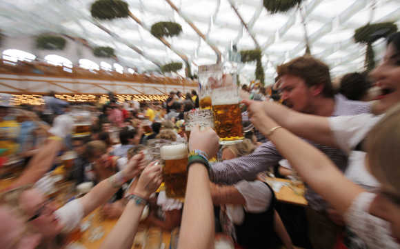 People wearing traditional Bavarian clothes toast with beer during the opening day of the Oktoberfest in Munich.