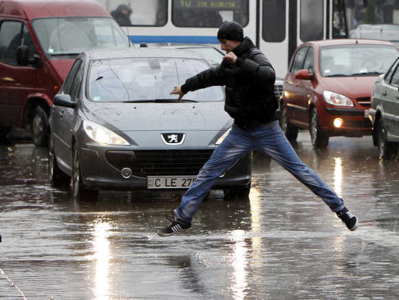 A man crosses the street in the rain in Chisinau, Moldova.