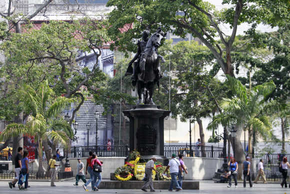 Poeple walk next to the statue of national hero Simon Bolivar at central Plaza Bolivar square in Caracas.