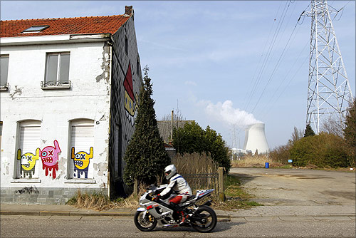 A motorcyclist rides past an abandoned house near the Doel nuclear plant.