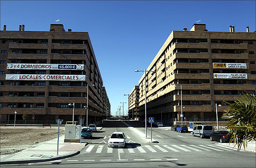 A car drives down the street near almost empty apartment blocks in the Madrid satellite town of Sesena.