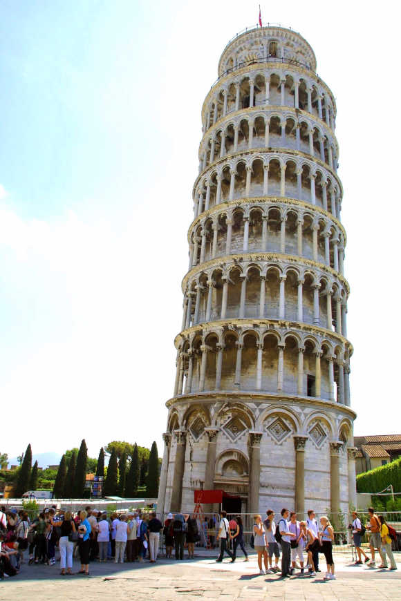 Tourists stroll under the famous leaning tower of Pisa.