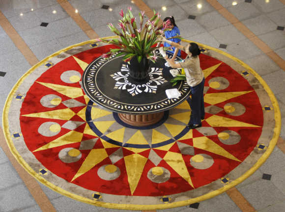Workers display a flower arrangement on a table at a hotel in Hanoi.