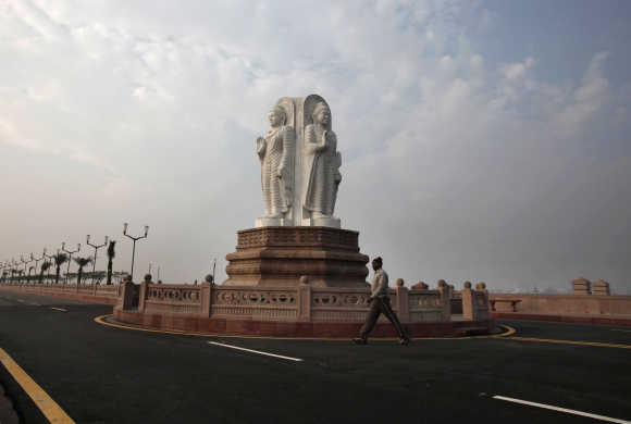 A man walks in front of Buddha statues outside the Ambedkar memorial park in Lucknow.