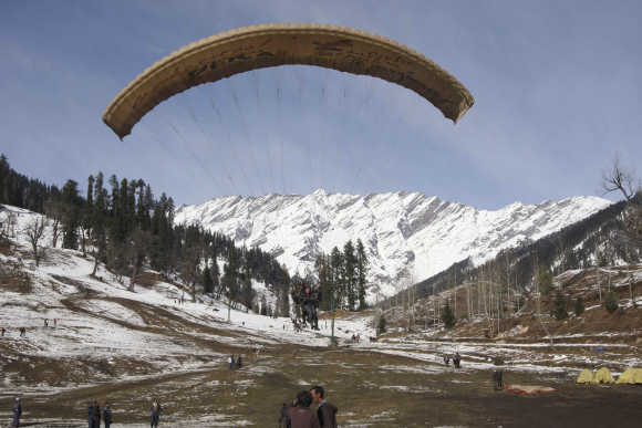 Tourists paraglide after fresh snowfall in Solang Nallah.