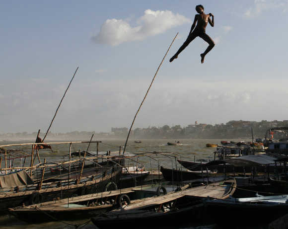 A boy jumps off a promenade into Ganga in Varanasi.