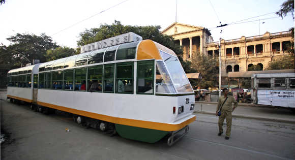 A conductor stands beside a tram in Kolkata.