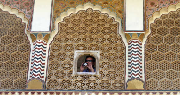A tourist takes pictures through a window of the Amber Fort in Jaipur.