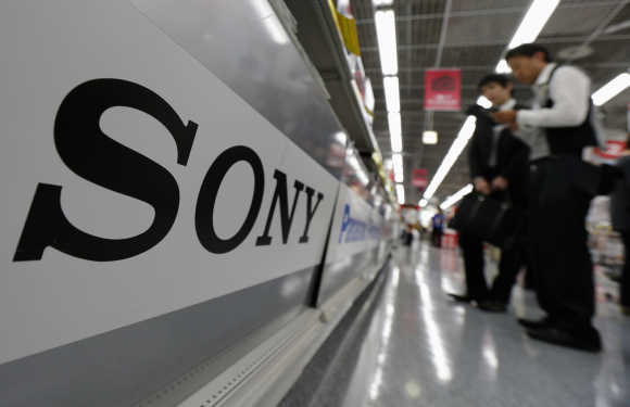 A Sony logo is seen as customers look at digital cameras at an electronic shop in Tokyo.