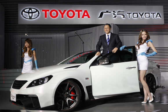 Akio Toyoda, President and CEO of Toyota Motor, poses with models at Toyota G's Reiz concept car during the Shanghai Auto Show.