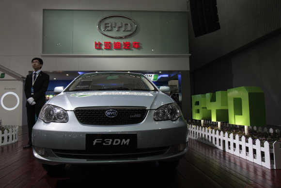 An employee stands near a F3DM, a hybrid car by Chinese automaker BYD Auto, at the Guangzhou Autoshow.