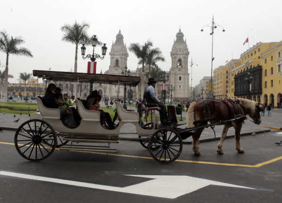 A man drives his horse-drawn carriage past the front of the presidential palace in Lima.