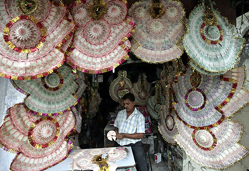 A shopkeeper staples Indian currency notes to make garlands at a market in Jammu.