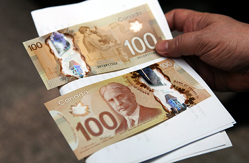 A man holds the new Canadian 100 dollar bills made of polymer in Toronto.