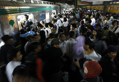 Passengers jostle to enter into a commuter train heading to their homes after work at the Tanah Abang train station in Jakarta.