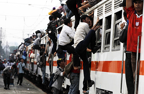 People climb up to the top of the roof of a train heading to their homes after work in Jakarta.