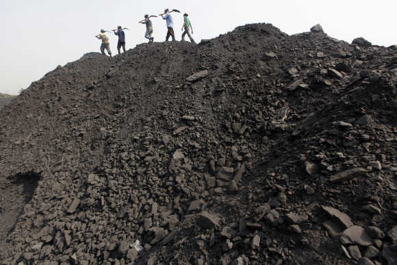 Workers walk on a heap of coal at a stockyard of an underground coal mine in the Mahanadi coal fields at Dera near Talcher town in Orissa.