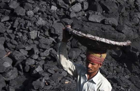 A labourer carries coal in a basket to load it in a truck at a coal store in Chandigarh.