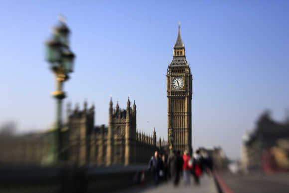 Pedestrians walk across Westminster Bridge in front of the Big Ben Clock Tower in London.