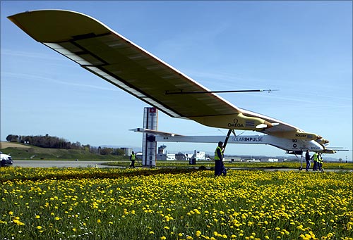 Staff push the Solar Impulse's solar-powered HB-SIA prototype airplane after a test flight at Payerne airport.