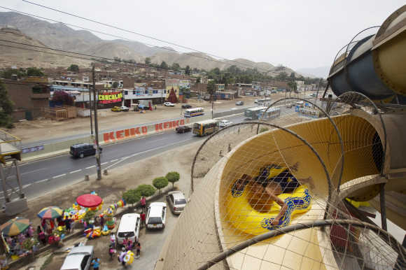 A boy slides down with a float at a big water slide at a water park in Lima.