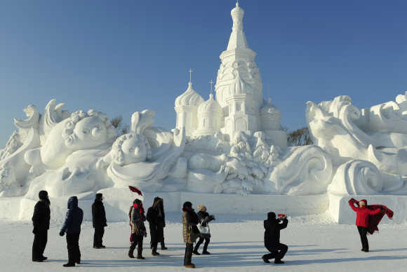 Tourists take pictures in front of a snow sculpture in Harbin, Heilongjiang province, China.