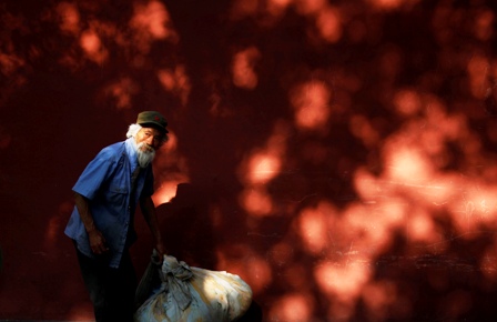 A homeless man lifts his belongings in front of a wall surrounding the Forbidden City in central Beijing.
