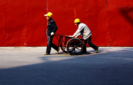 Migrant workers move a cart down a road near a construction site in Beijing.