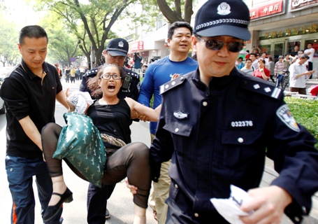 Police carry away a woman who started a protest for personal economic reasons in front of the media outside Chaoyang Hospital in Beijing.