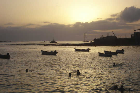 Children play in the water at sunset in the port of Sal Rei in Cape Verde.