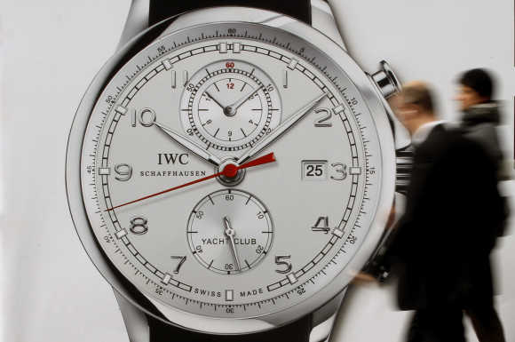 People walk past an advertising poster of Swiss watch manufacturer IWC International Watch Co in Zurich.