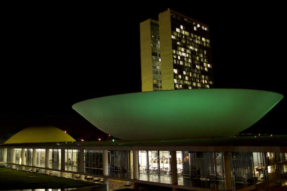 National Congress building in Brasilia is illuminated with green and yellow lights.