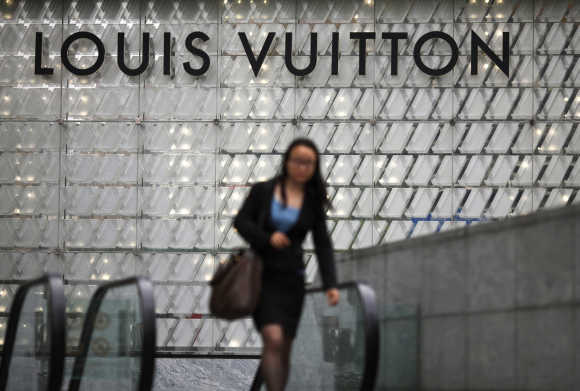 A woman walks by a Louis Vuitton luxury boutique at the IFC Mall in Shanghai.