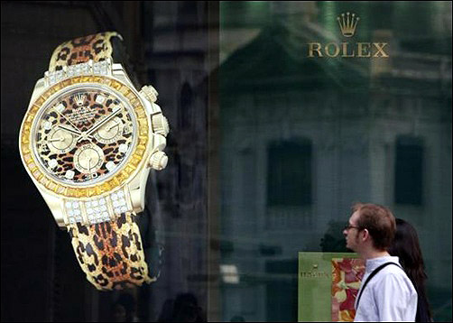 Foreign visitors walk past a watch brand advertisement.