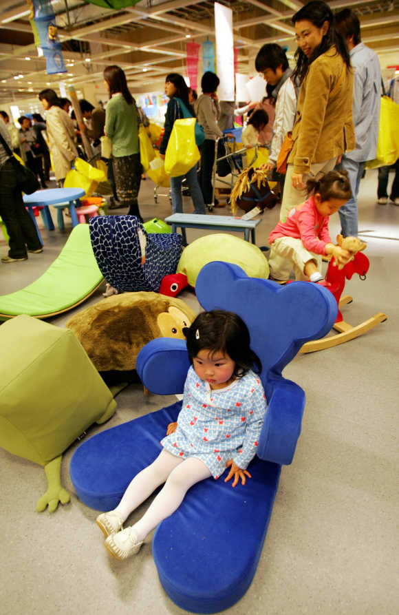 A girl rests on Ikea's teddy bear shaped chair at the company's store in Japan in Funabashi, east of Tokyo.