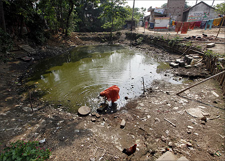 A woman washes her utensils in a polluted pond at Singur, north of Kolkata.
