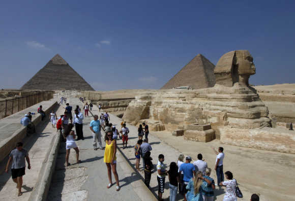 Tourists take pictures at the Sphinx and the Pyramids of Giza in Cairo.