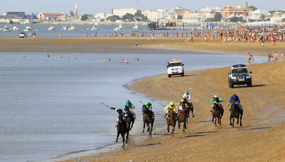 Jockeys take part in a race along the beach during low tide in Spanish town of San Lucar de Barrameda.