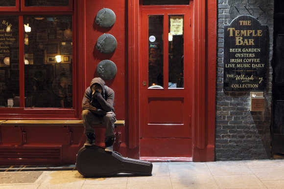 A musician sits on a bench outside a pub in Temple Bar, Dublin.