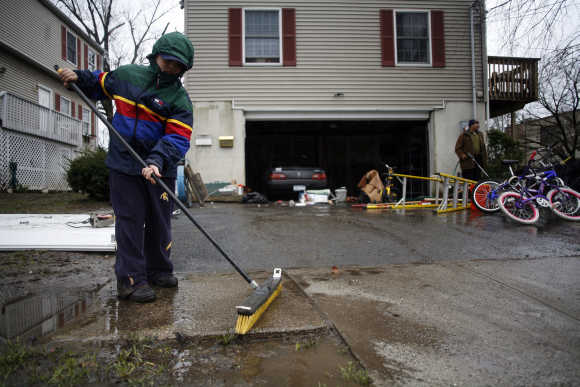 Pablo Martinez cleans up mud in front of his home in Mamaroneck, New York.