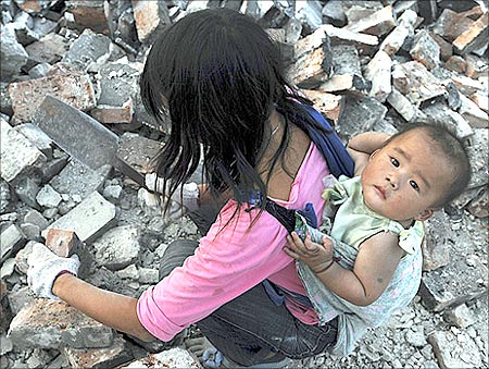 A migrant worker collects bricks as she carries her child on her back, at a demolition site in Jiaxing, Zhejiang province.