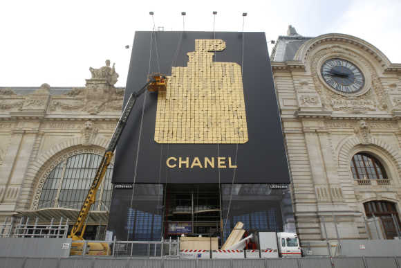A crane removes a huge advertisement for Chanel No. 5 perfume installed on the facade of the Musee d'Orsay in Paris.