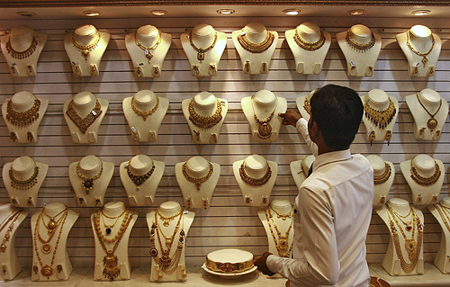 A salesman arranges a gold necklace inside a gold jewellery showroom in Kochi.